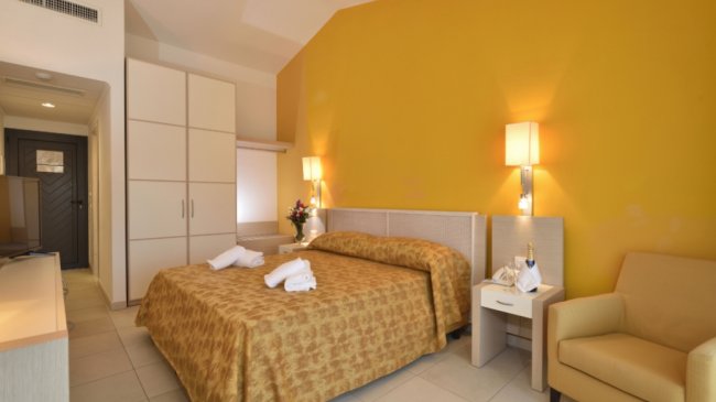 Stanza con letto matrimoniale e seduta beige.