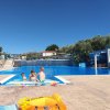 Bambini che giocano in piscina con scivolo e giochi gonfiabili.
