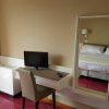 Una scrivania con monitor e sedia, accanto a un letto riflesso nello specchio.