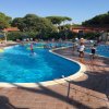 Piscina all'aperto con persone che nuotano e giocano intorno.