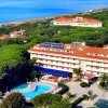 Hotel con piscina, immerso nel verde, vista mare sullo sfondo.