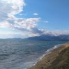 Spiaggia con mare calmo e montagne sullo sfondo.