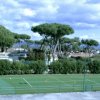 Campo da calcio recintato con alberi sullo sfondo.