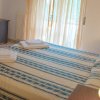 Camera con letto matrimoniale, copriletto a righe blu, scrivania e lampada accesa.