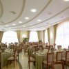 Sala ricevimenti elegante con tavoli rotondi apparecchiati, finestre grandi e soffitto ondulato.