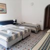 Camera d'albergo con quattro letti singoli, arredamento semplice, e pavimento piastrellato.