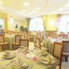 Sala decorata per festa con tavoli rotondi, tovaglie eleganti e palloncini rosa e bianchi.