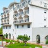 Un edificio bianco con balconi e un giardino curato con alberi e un patio.