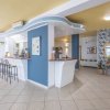 Una reception moderna con bancone curvo, sedie alte e pareti decorate con piante e dipinti.