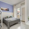 Una camera d'albergo con letto matrimoniale, letti a castello e piante. Parete blu e porta finestra.