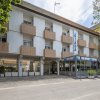 L'esterno di un edificio con balconi quadrati e una veranda vetrata, con piante all'ingresso.