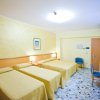 Una camera d'albergo con tre letti singoli coperti da coperte beige.