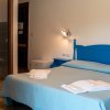 Camera con letto matrimoniale blu, bagno in vista, lampada da parete e asciugamani piegati.