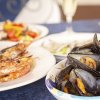 Una tavola con cozze e piatti di pesce alici e gamberi.