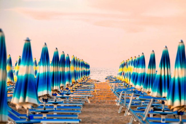 Ombrelloni chiusi su spiaggia al tramonto.