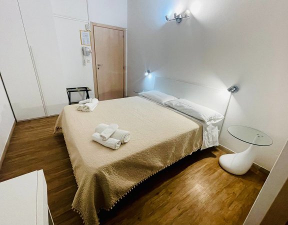 Camera con letto matrimoniale e lenzuola beige.