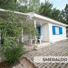 Una casa bianca con infissi blu e piante tropicali.