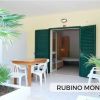Terrazza con tavolo, sedie bianche e piante tropicali.