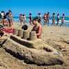 Ragazzi costruiscono un castello di sabbia sulla spiaggia.