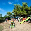 Parco giochi con scivoli colorati tra gli alberi.
