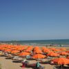 Spiaggia con ombrelloni arancioni e mare calmo.
