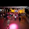 Persone che ballano sotto luci colorate in un palco all'aperto.