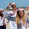 Persone in costume da marinaio che salutano sulla spiaggia.