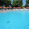 Grande piscina con lettini e ombrelloni arancioni.