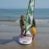 Bambino su tavola da windsurf sulla spiaggia.