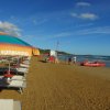 Ombrellone colorato su una spiaggia sabbiosa con lettini e mare calmo.