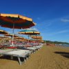 Ombrelloni colorati e lettini allineati su una spiaggia soleggiata.