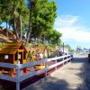 Area giochi per bambini con casetta e altalene, circondata da alberi.