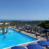 Una grande piscina all'aperto con ombrelloni blu, circondata da lettini, vista mare.