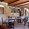 Ristorante rustico con pareti in pietra, tavoli coperti da tovaglie a quadretti.