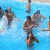 Persone che si divertono in una piscina, spruzzando acqua.
