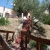 Scala rossa in pietra tra cactus e alberi, conduce a un barbecue in muratura su una terrazza.