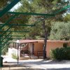 Un bungalow rosa con veranda immerso tra gli alberi, con strutture verdi in primo piano.