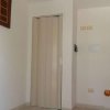 Angolo di una stanza con porta pieghevole beige, quadro appeso e parte della cucina.