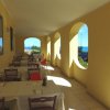 Veranda con tavoli apparecchiati, archi e vista sul mare.