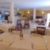 Sala da pranzo con tavoli apparecchiati e sedie di legno in un ambiente luminoso.