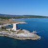 Torre su un promontorio roccioso sul mare, circondata da paesaggio costiero.