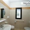 Bagno con specchio rotondo e finestra.