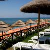 Lettini sotto ombrelloni di paglia vicino al mare.