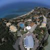 Vista aerea di un resort sul mare con piscina e campi verdi.