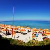 Spiaggia con ombrelloni arancioni e gialli, mare cristallino.