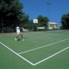 Una persona gioca a tennis su un campo all'aperto.