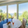 Tavolo apparecchiato vicino a finestre con vista mare e giardino.