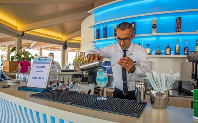Barista prepara un cocktail blu al bar della piscina.
