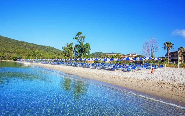 Spiaggia sabbiosa con ombrelloni blu e bianchi.