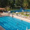Piscina all'aperto con bagnanti e ombrelloni.